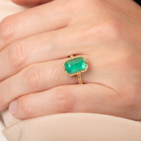Gold ring with an emerald gemstone on a hand