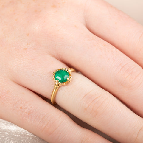 Gold ring with an emerald gemstone on a finger