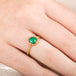 Gold ring with an emerald gemstone on a finger