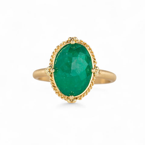 Gold ring with an emerald gemstone on a white background