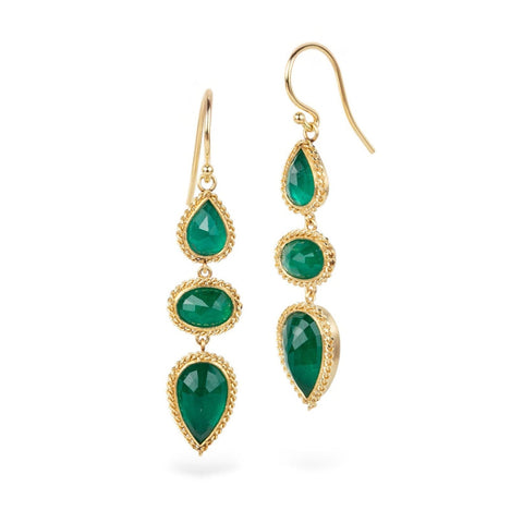 Gold earrings with emerald gemstones on a white background