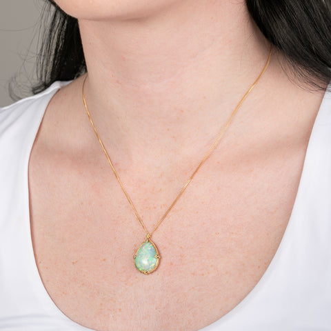 Ethiopian opal teardrop pendant necklace with gold setting on a person