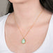 Ethiopian opal teardrop pendant necklace with gold setting on a person
