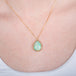 Ethiopian opal teardrop pendant necklace with gold setting on a person