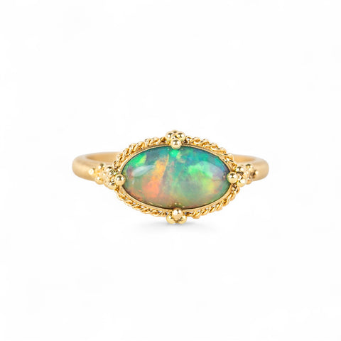 Gold ring with an Ethiopian opal stone on a white background