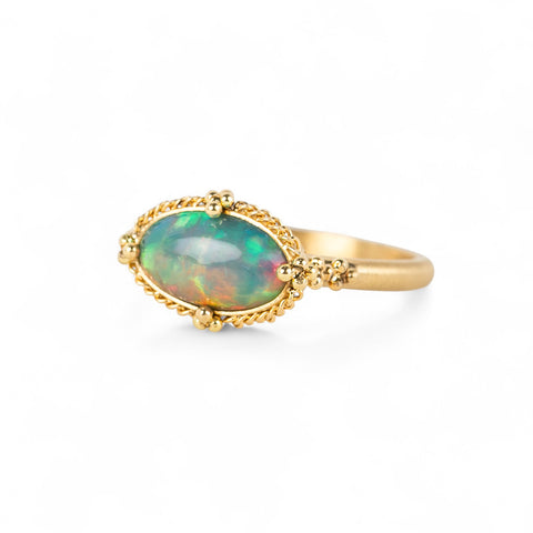 Gold ring with an Ethiopian opal stone on a white background