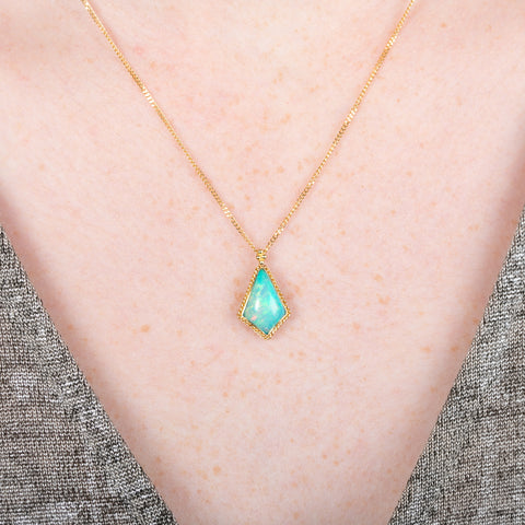 Gold necklace with an Ethiopian opal gemstone pendant on a person