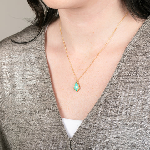Gold necklace with an Ethiopian opal gemstone pendant on a person