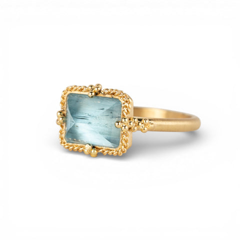 Gold ring with a blue aquamarine stone on a white background