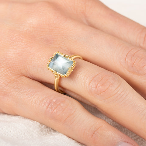 Gold ring with a blue aquamarine on a person's finger