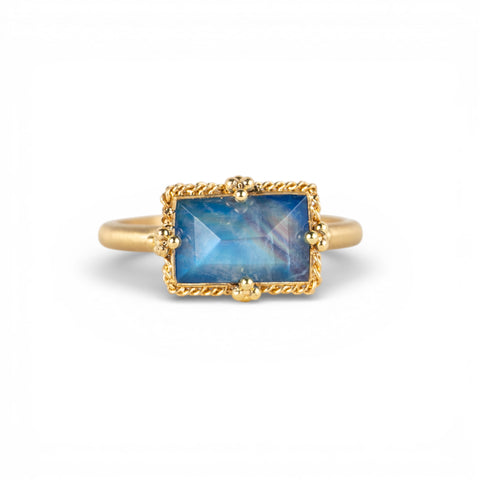 Gold ring with a blue moonstone on a white background