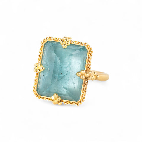 Gold ring with a large aquamarine gemstone on a white background