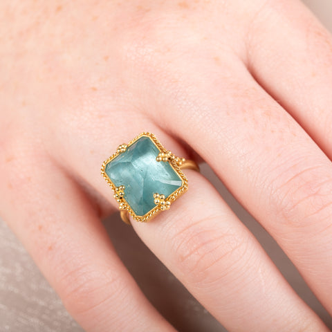 Gold ring with a large aquamarine gemstone on a person's hand