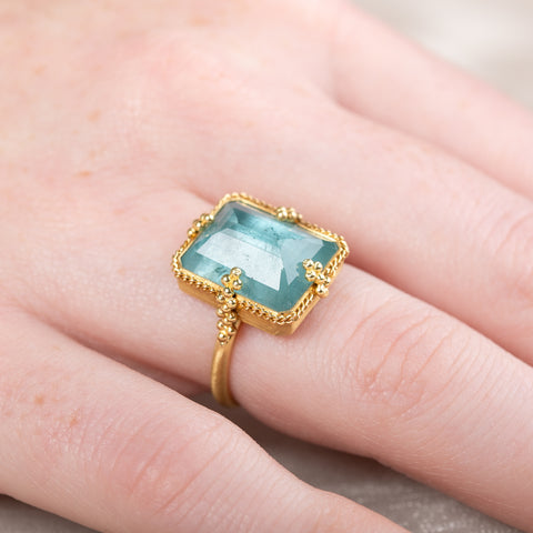 Gold ring with a large aquamarine gemstone on a person's finger