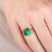 Gold ring with an emerald gemstone on a finger