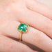 Gold ring with an emerald gemstone worn on a finger