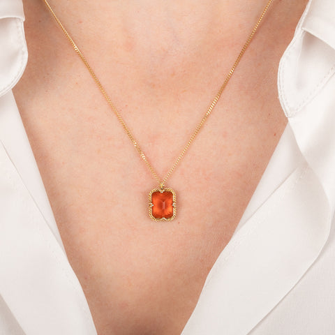 Gold necklace with a fire opal gemstone on a person