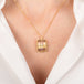 Gold necklace with a rectangular fluorite gemstone worn by a person in a white outfit.
