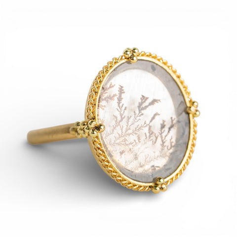 Gold ring with a dendritic quartz stone  on a white background