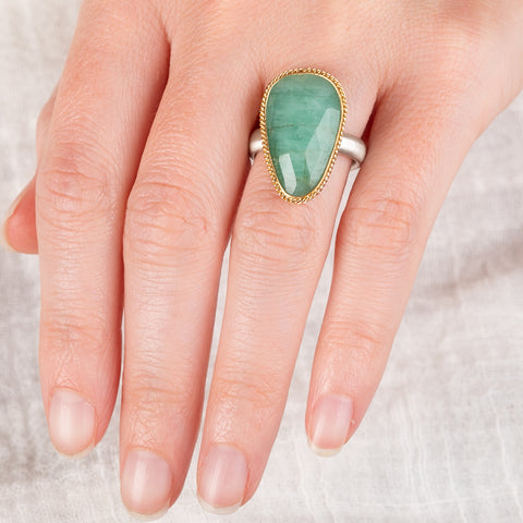 Ring featuring an emerald gemstone set in an 18k gold bezel with a silver band 