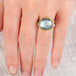 Hand wearing an aquamarine ring with 18k gold bezel and sterling silver band on white background