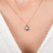Gold necklace with a moonstone pendant on a person wearing a white garment.
