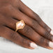 Hand wearing a gold ring with an Oregon sunstone gemstone on a light background