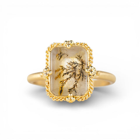Gold ring with a rectangular dendritic quartz stone on a white background