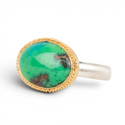 A gold and silver ring featuring an oval gem silica stone on a plain white background.