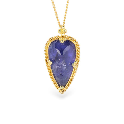 Indigo tanzanite teardrop-shaped gemstone pendant on a gold chain against a white background
