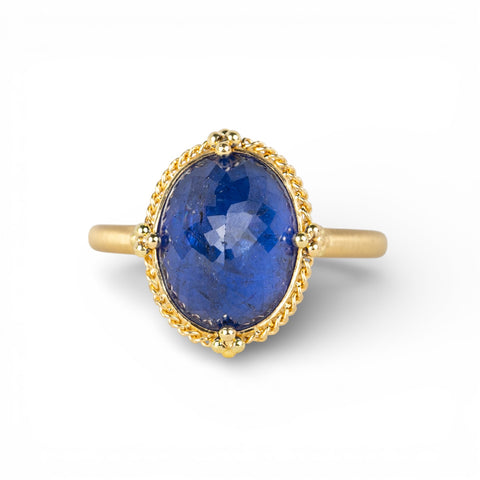 Gold ring with a blue tanzanite gemstone on a white background