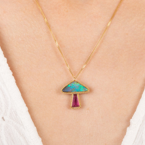 Gold mushroom necklace with a tourmaline and boulder opal stone on a person