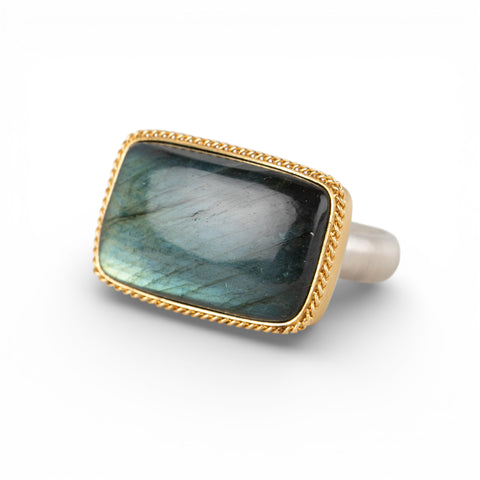 Gold and silver ring with a rectangular labradorite stone on a white background