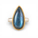 Ring with a teardrop-shaped labradorite gemstone and gold bezel with silver band on a white background