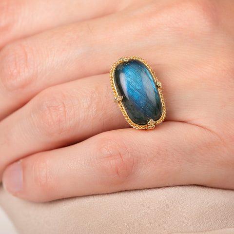 Gold ring with a labradorite gemstone on a person's finger
