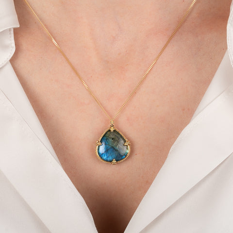 Necklace with a Labradorite pendant worn by a person in a white shirt