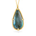 Teardrop-shaped labradorite pendant with gold frame on white background