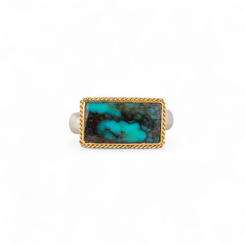 Turquoise ring with gold bezel and sterling silver band on white background