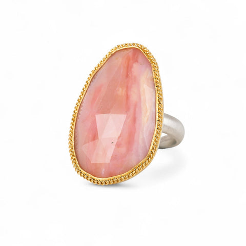 Handcrafted ring with rhodochrosite stone, gold setting and silver band on a white background
