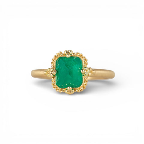 Gold ring with an emerald gemstone on a white background