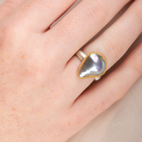 Mabe Pearl ring with gold bezel and silver band on a person's finger