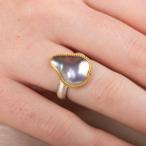 Mabe Pearl ring with gold bezel and silver band on a person's finger