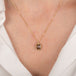 Gold necklace with a brown diamond pendant on a person wearing a white shirt