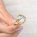 Gold ring with a topaz stone held by a hand on a light background