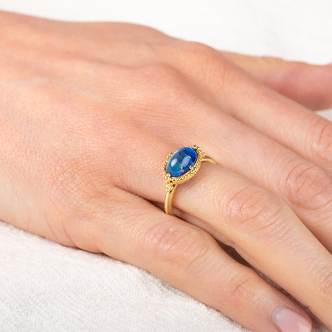 Gold ring with a moonstone on a hand against a white background