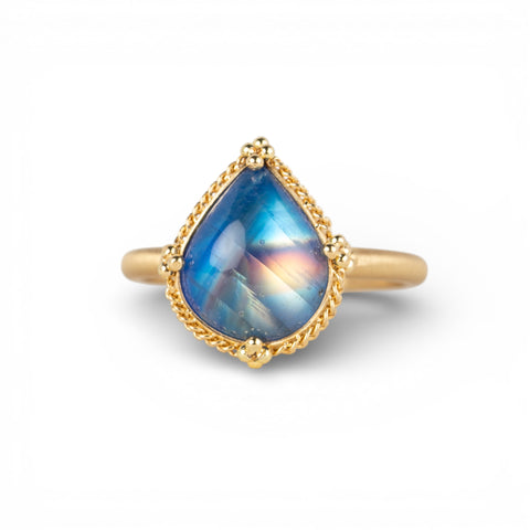 Gold ring with a blue teardrop-shaped moonstone on a white background