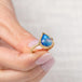 Gold ring with a blue teardrop-shaped moonstone held in hand