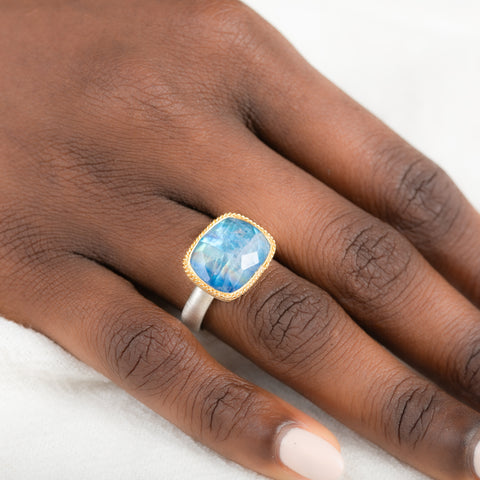 Gold and silver ring with a moonstone on a person's finger