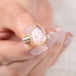 Gold and silver ring with pink morganite teardrop-shaped gemstone held in hand