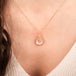 Gold necklace with a morganite teardrop pendant on a person's neck